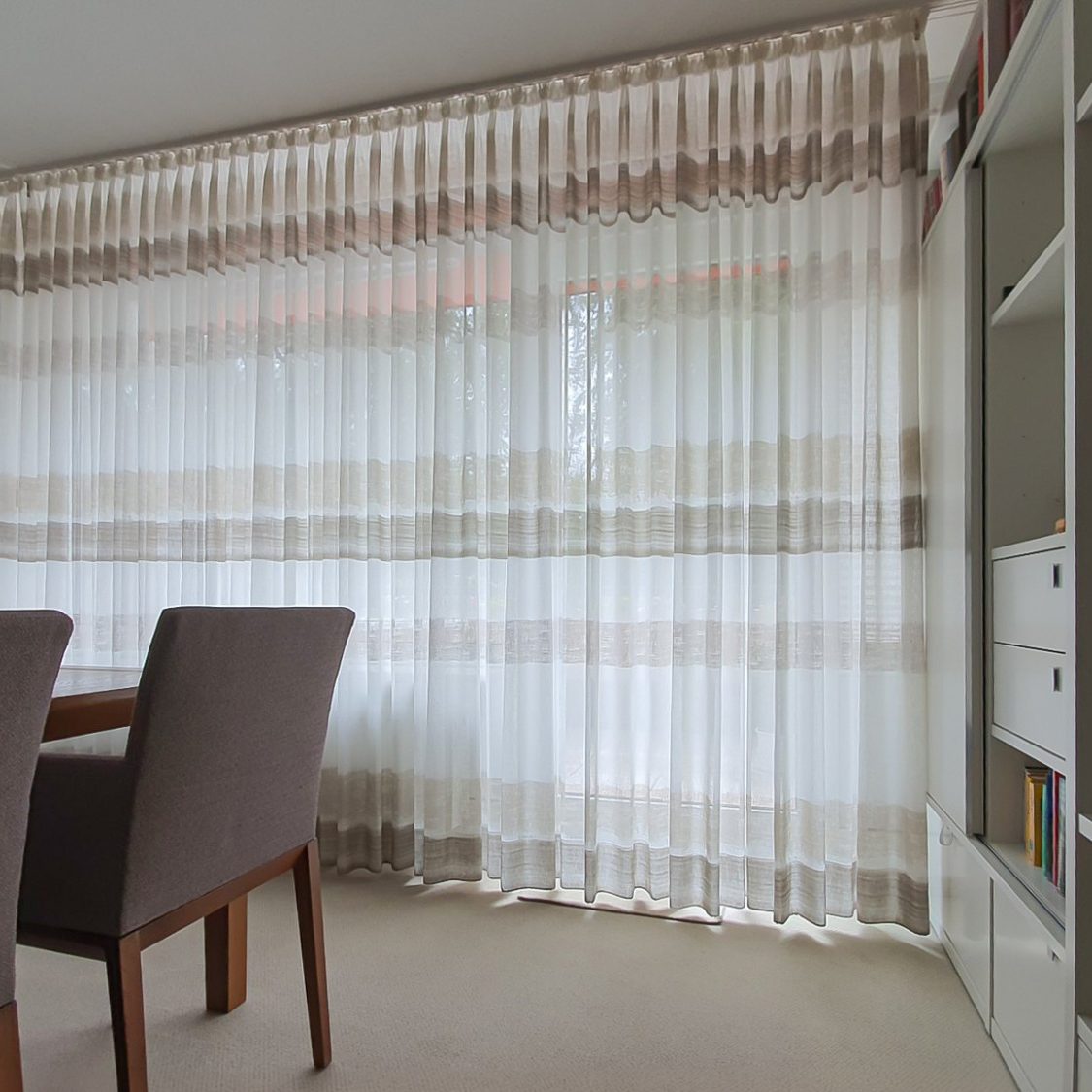 Transparente Gardine mit gestreiftem Muster vor einem Fenster im Esszimmer